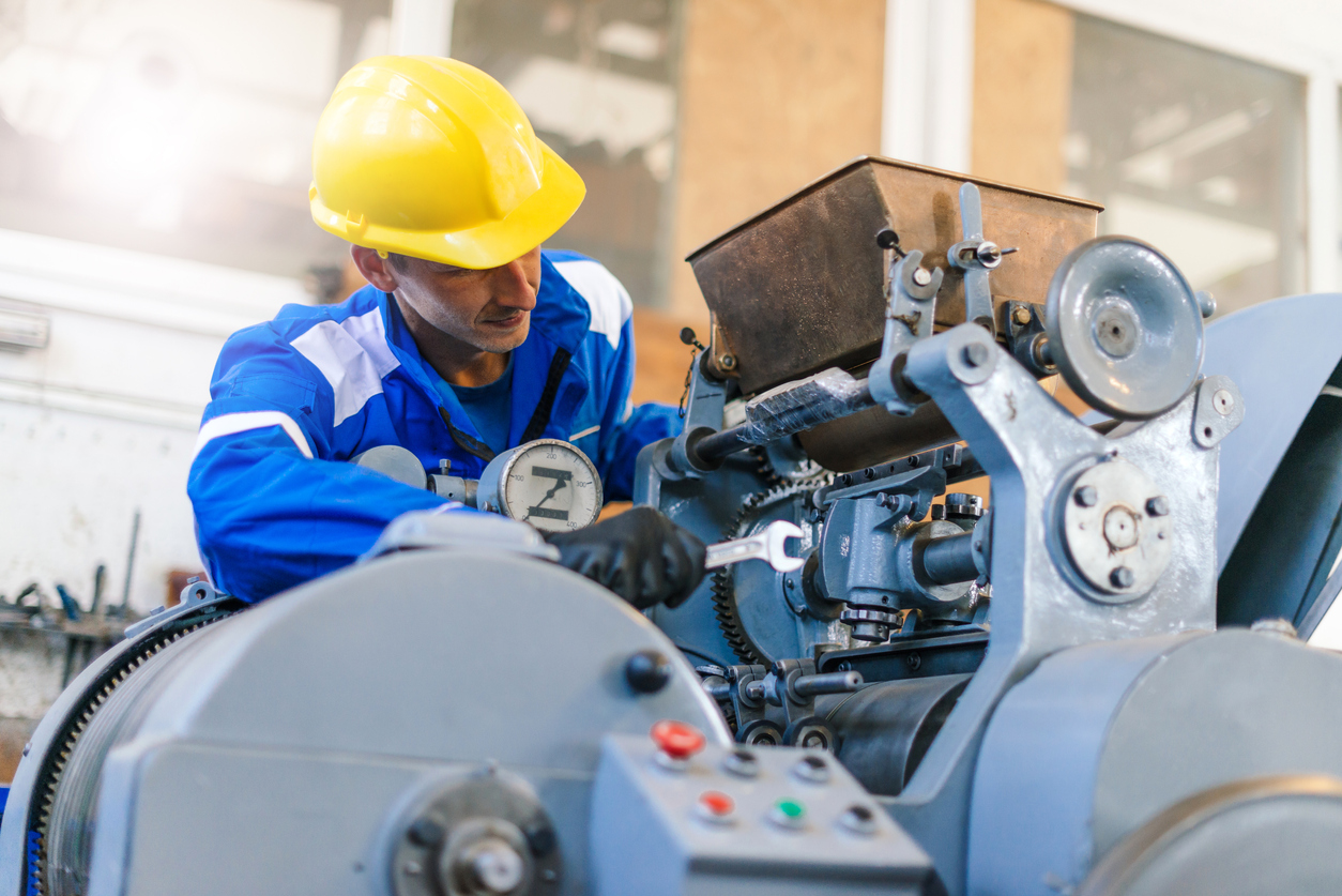 A machine operator holding a wrench to conduct preventive maintenance of a machine