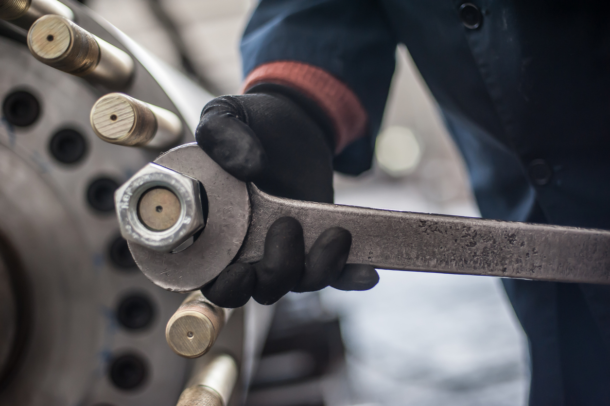 Mechanic repairman at the factory screws big bolt with large and heavy wrench key