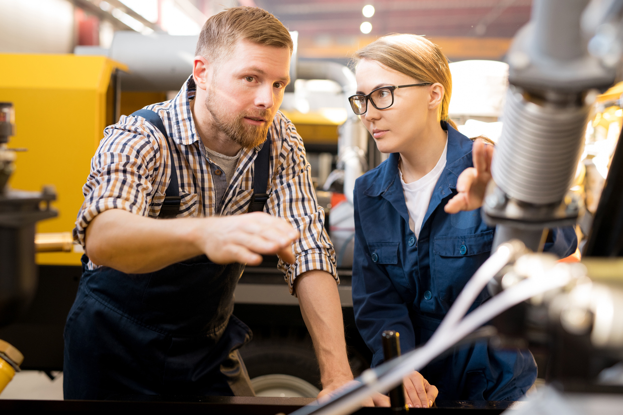 A female machine technician instructs a machine operator for corrective maintenance of an equipment