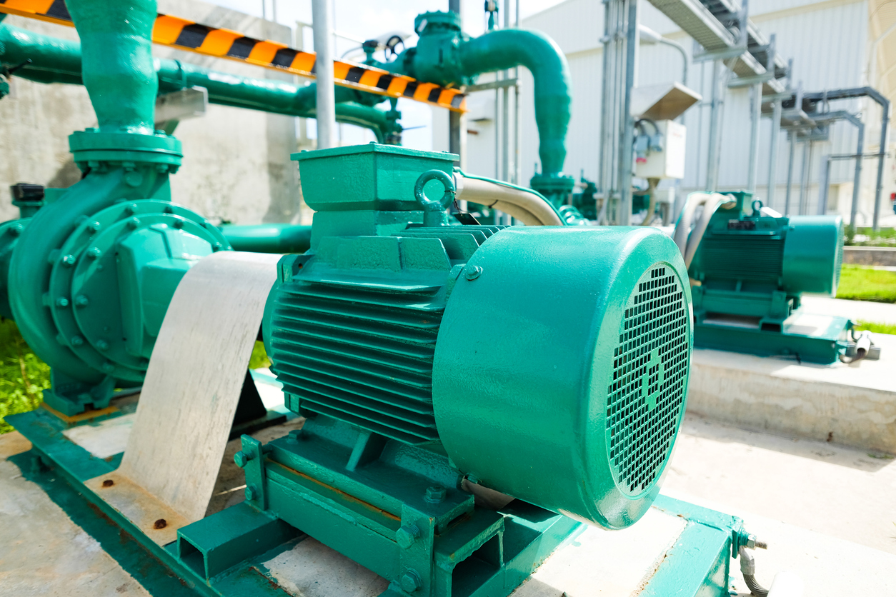 A turquoise centrifugal pump sits unused on the working floor of a heavy industrial business